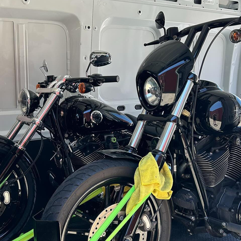 Two black cruiser motorcycles strapped side by side in a van