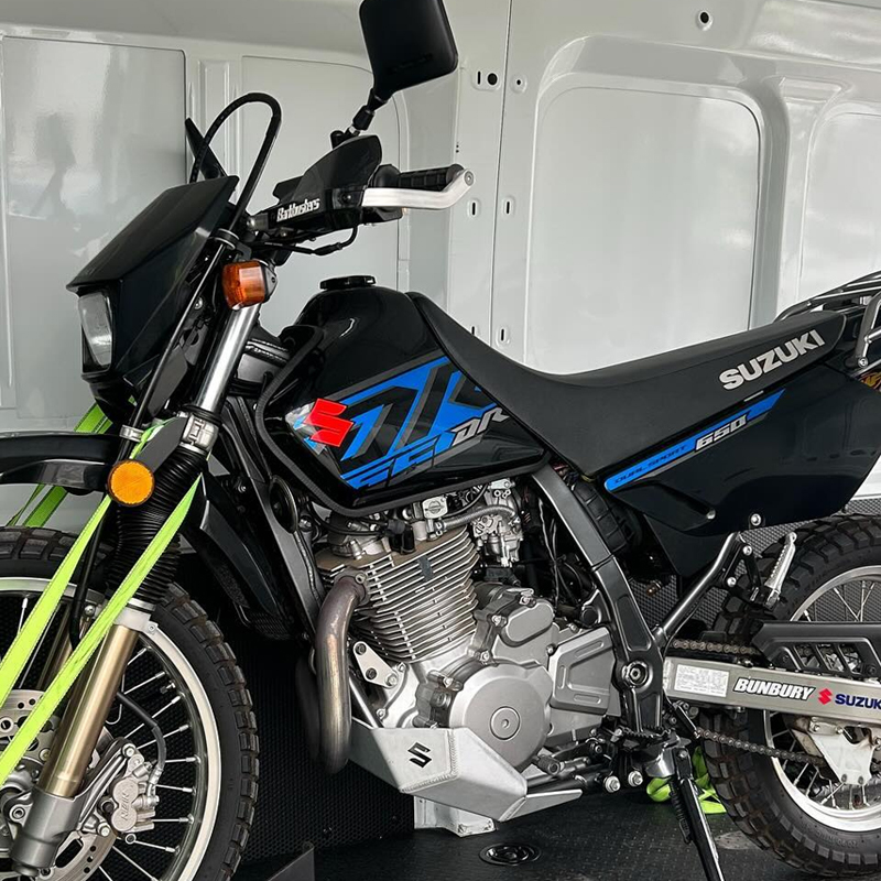 Black and blue Suzuki dirt bike strapped down inside a van