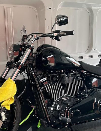 Black cruiser motorcycle with a yellow cloth on the fork inside a van