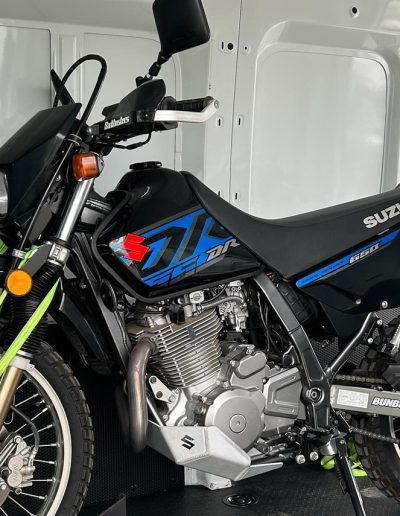Black and blue Suzuki dirt bike strapped down inside a van