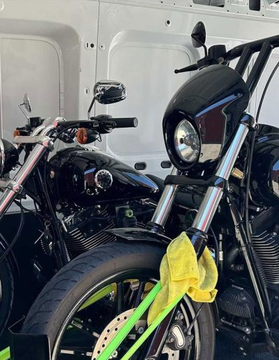 Two black cruiser motorcycles in a van beside the open side door, wider view