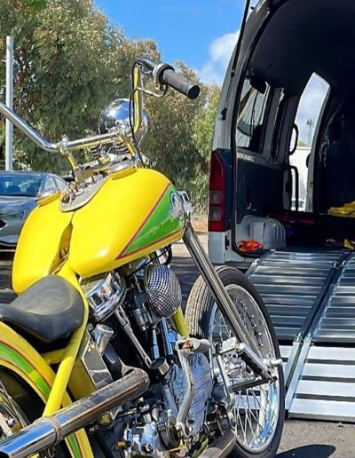Yellow and green custom chopper beside a van with an aluminium loading ramp