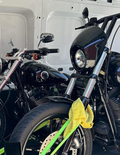 Two black cruiser motorcycles strapped side by side in a van