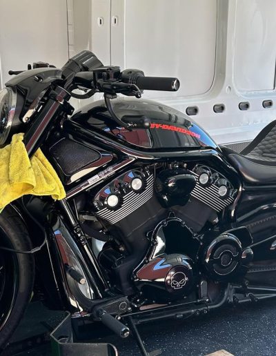 Black cruiser motorcycle with red tank lettering strapped inside a van