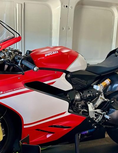 Red and white Ducati sports bike loaded inside a van