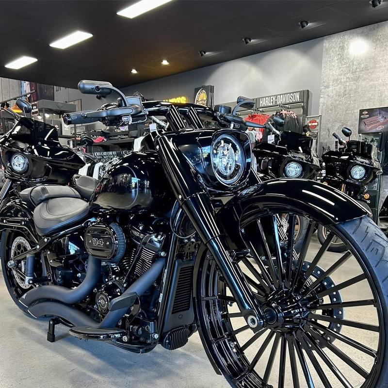 Black custom motorcycle with a large spoked front wheel in a showroom