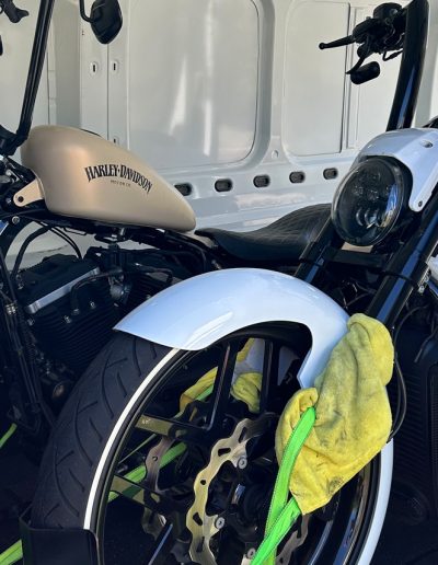 Beige-tanked Harley-Davidson and a white motorcycle strapped down inside a van
