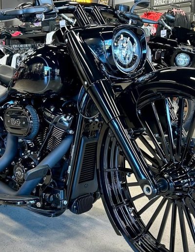Black custom motorcycle with a large spoked front wheel in a showroom